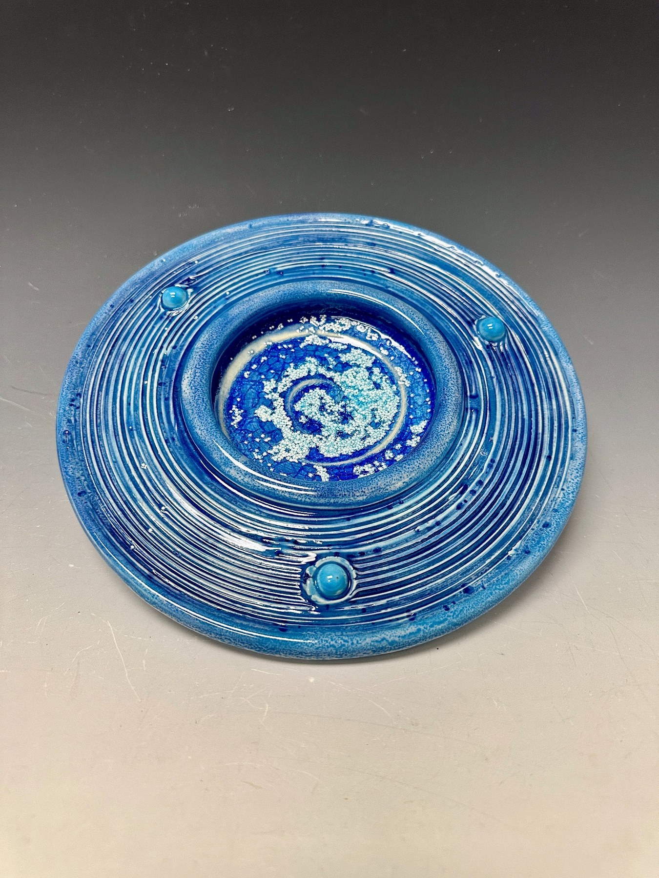 Atmospheric Blues, a shallow blue circular porcelain form with a crystalline spiral center.
