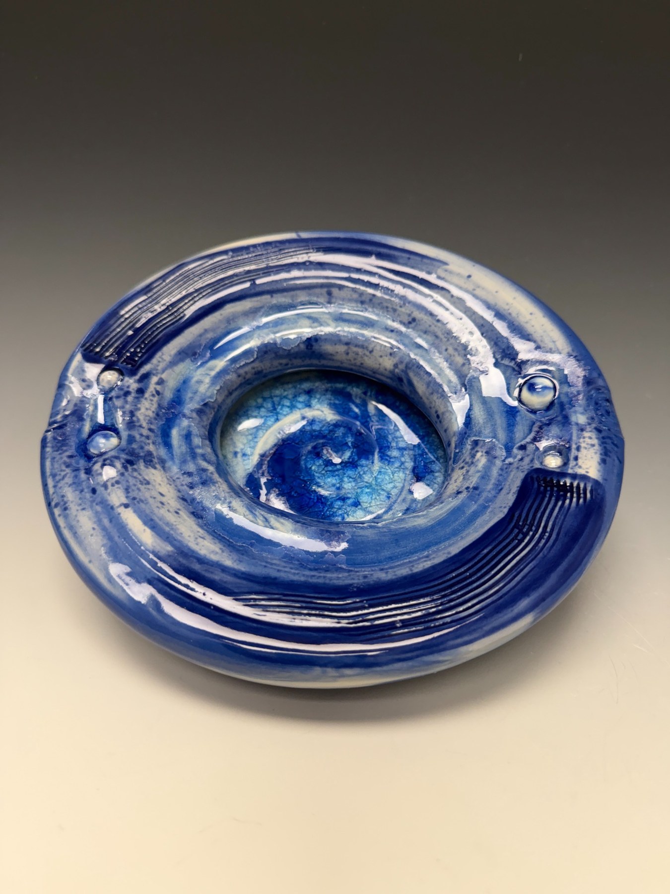 Blue Compression Form, a low circular blue porcelain form with spiral center.