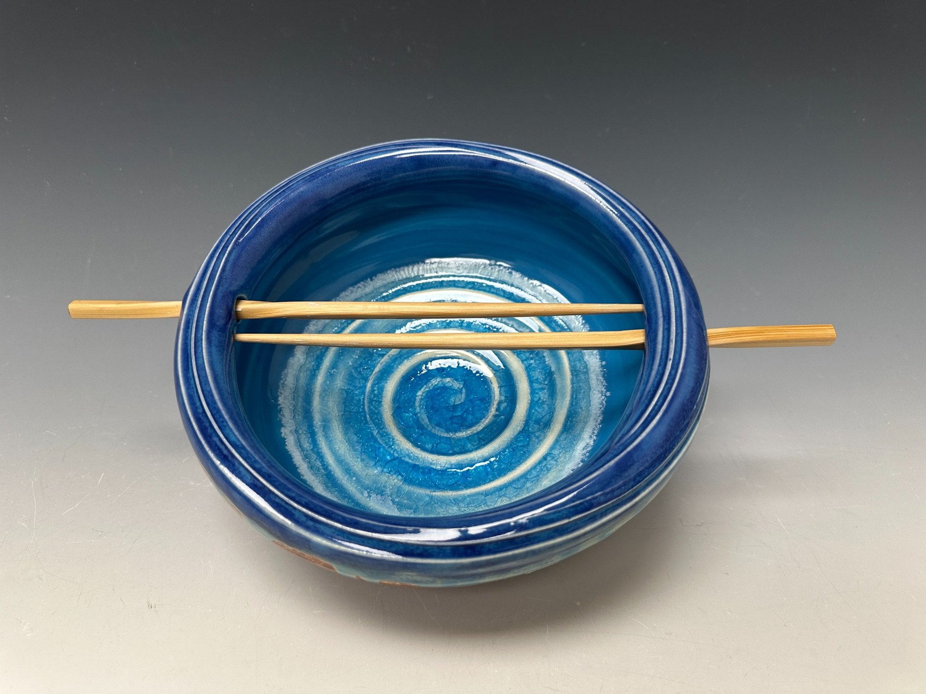 Blue Cosmic Bowl with two chopsticks spanning the opening.