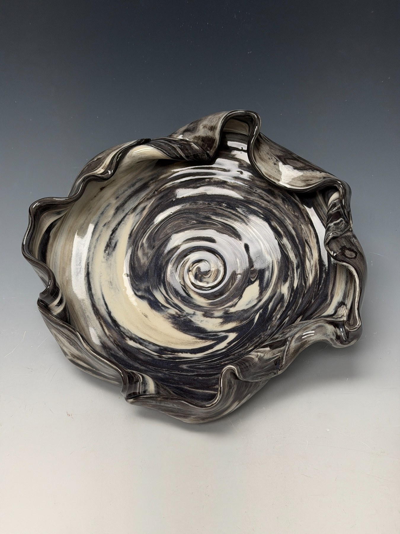 Dancing Fog Bowl, a black and white porcelain vessel with an undulating rim and spiral center.