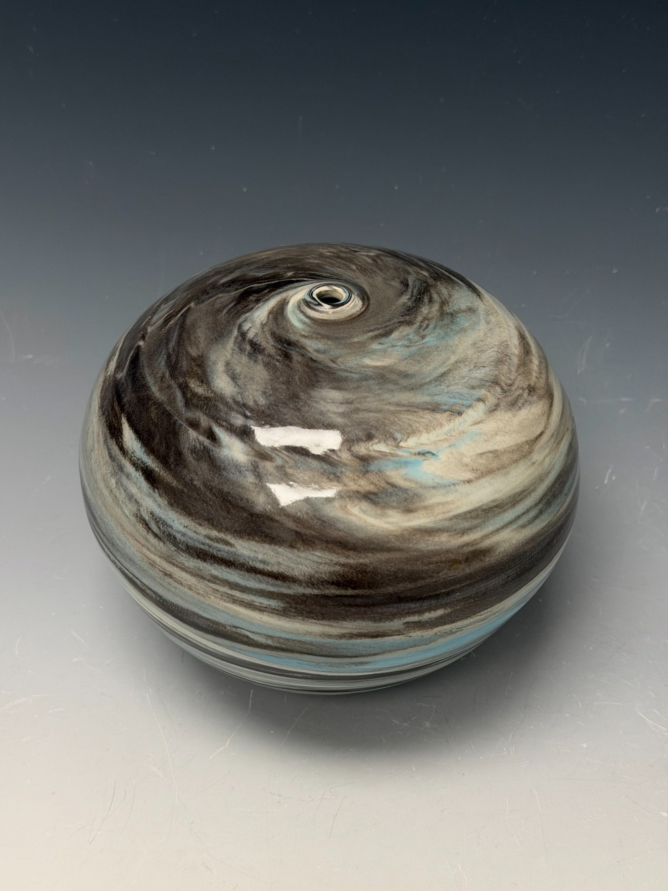 Foggy Planet Sphere, a rounded porcelain vessel with dark gray, ivory, and pale blue swirling bands.