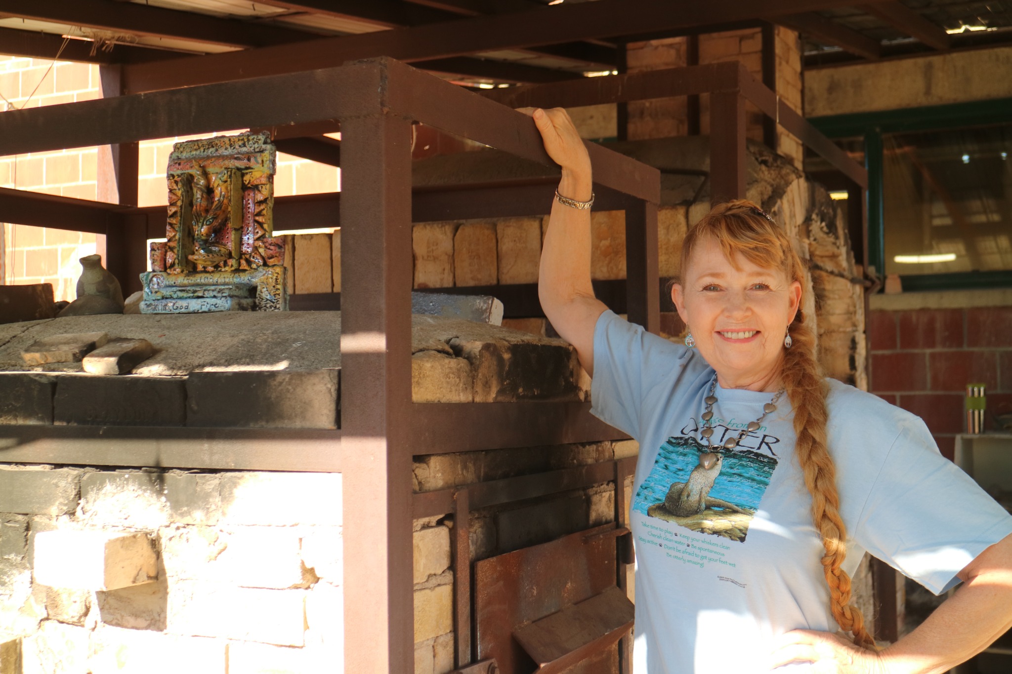 Martie beside a Medalta kiln with her donated kiln god sculpture.