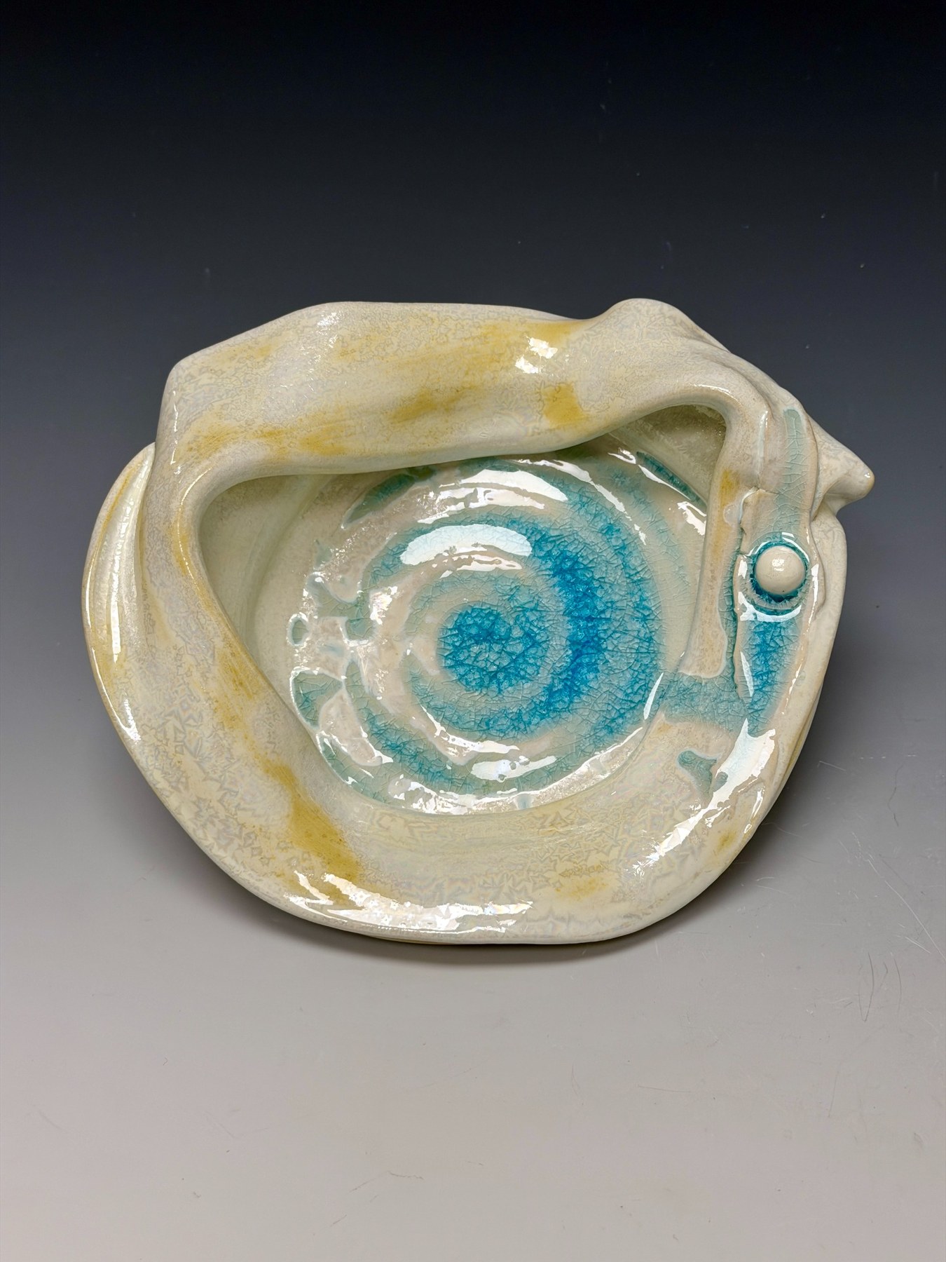 Solar Water, a cream porcelain form with a turquoise spiral pool and irregular folded rim.