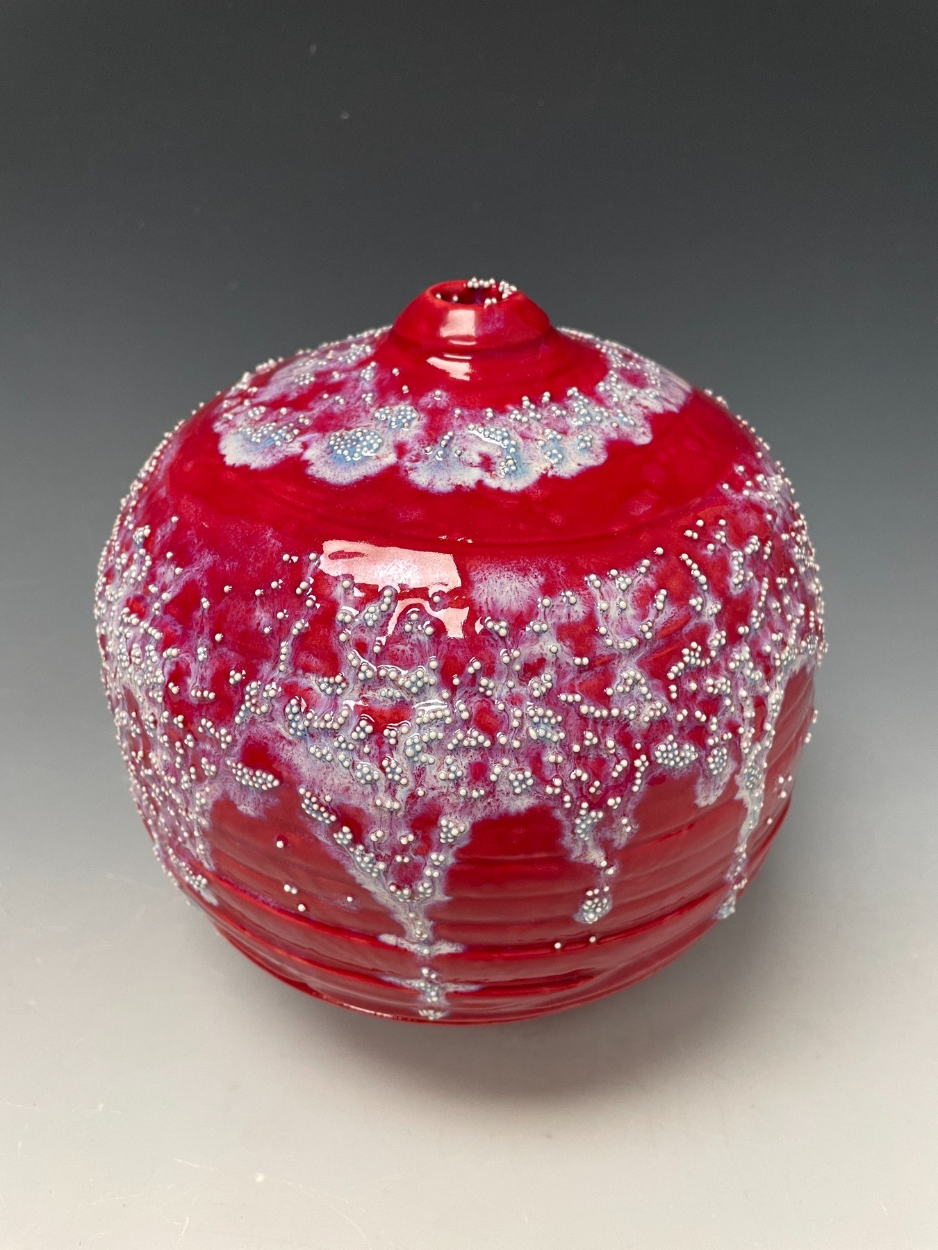 White Sands Over Red, a vivid red porcelain sphere with white crystalline and porcelain-sphere surface details.